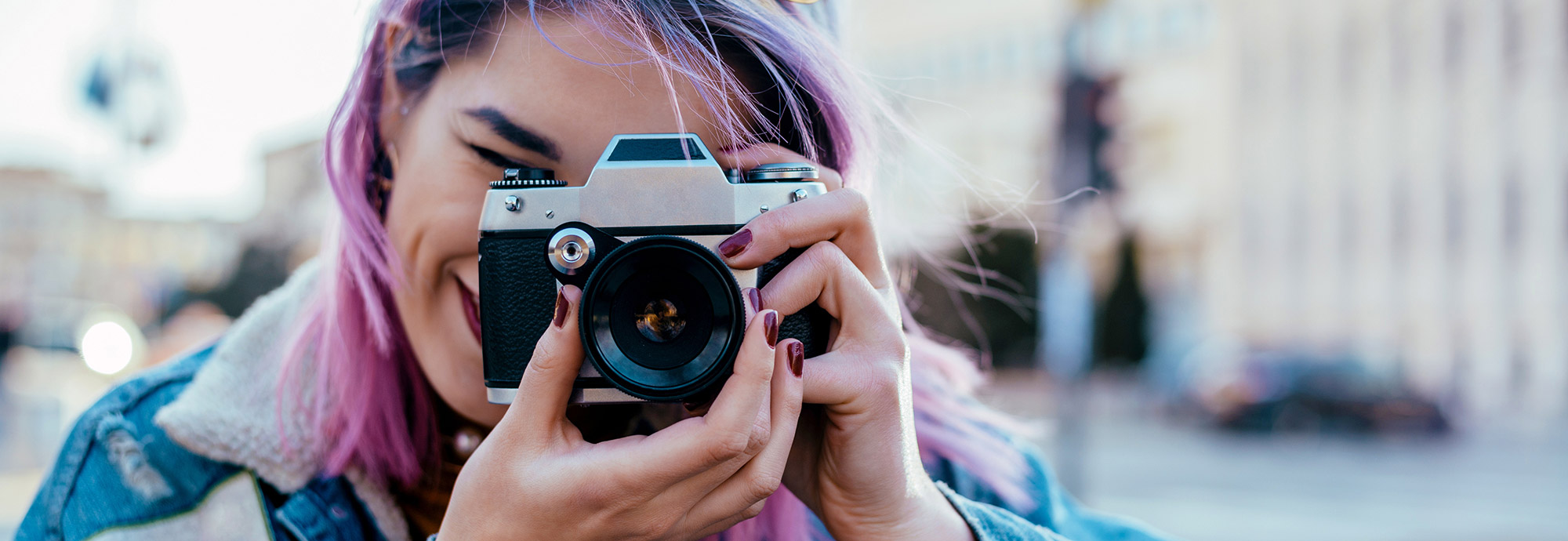 A young person holding up a camera taking a photo for the Feel Out Loud Community Creator Space at Kids Help Phone